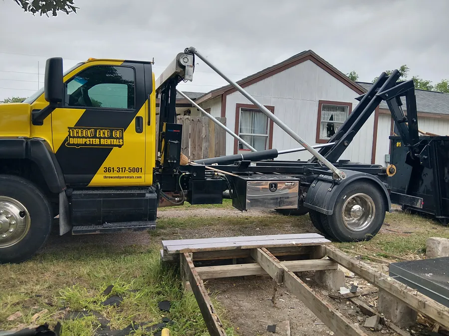 Roll-off dumpster being loaded with construction cleanout debris in Corpus Christi